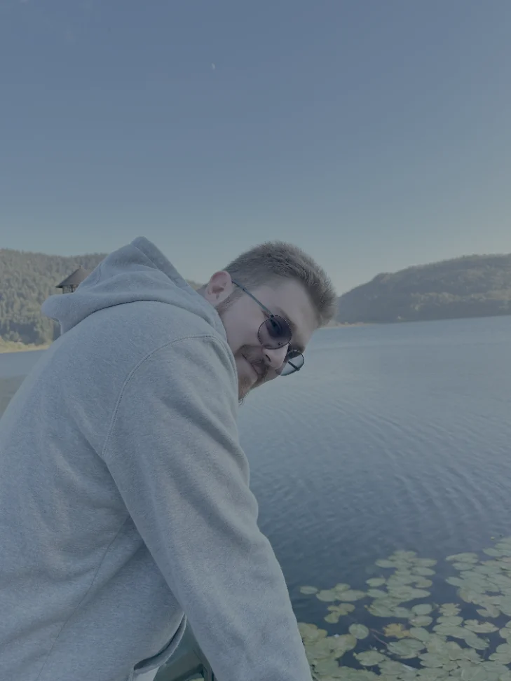 Bartu Yaman leaning on a railing above a lake